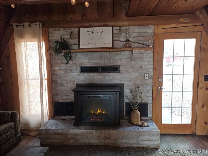 Nestled in the woods on 1.6 peaceful acres, this charming A-frame cabin offers the perfect retreat for outdoor enthusiasts. BorderingCorp ground and located just minutes from Truman Lake with easy access at the Old Timers Boat Ramp, this property is a fisherman’sor hunter’s dream. The main level features warm wood floors and knotty pine walls that create a truly cozy, cabin-style atmosphere. Theliving room showcases a beautiful fireplace surrounded by stone, with an open ceiling that extends to the roof, highlighting the classic A-frame design. A convenient half bath is also located on the main level. Upstairs, the loft bedroom overlooks the living space and provides a comfortable and inviting sleeping area. The partially finished full walkout basement adds additional living space and includes a full bathroom and a laundry area, making the cabin ideal for extended stays or weekend getaways. Utilized as a 2nd bedroom and rec room. Offered fully furnished, this cabin is ready to enjoy from day one. Whether you’re seeking a private escape, a hunting base, or a fishing getaway near the lake, this property delivers rustic charm, comfort, and an unbeatable location.