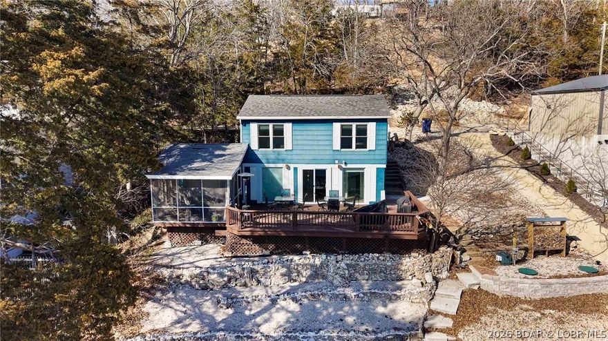 This Country Cabin on the Lake of the Ozarks is the ideal place to start making lake memories with friends and family! You'll feel blessed to own this charming blue bungalow perched on the water's edge. Take in the awesome views from the oversized deck or the screened-in porch. Easy walk down to the 2 well dock with swim platform and storage in YEAR-ROUND deep water! The boat house is very convenient for additional storage for floats and fishing poles. The home offers 3 bedrooms and 2 baths as well as a bonus heated and cooled sleep space for extra room for family and friends. This home comes with furniture included. All major renovations have been done, including new well and septic. Summer fun starts here. Call today, and you will be a lake home owner before spring! By water close to Jolly Rogers, Coconuts, and Tap and Grill. Rentals are allowed! Ask your lender about a DSCR loan for cash flow properties!