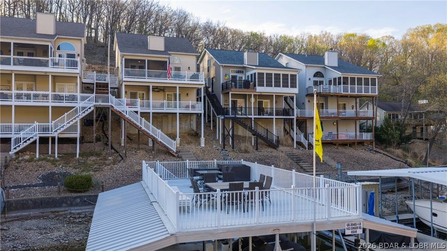 Welcome to easy lake living with this 5 bedroom, 3.5 bath home tucked inside a calm, protected deep water cove with a setting that offers a peaceful easy feeling and convenient access to the lake. This cove is perfect for fishing, kayaking, or paddleboarding, and your upper dock deck is the perfect spot for fun summer days with friends. The main level offers a rare single car garage with owners suite and open concept living kitchen and dining. The fireplace splits access to both a covered screened porch perfect for dining and an uncovered area for open air and grilling. The upper level features 2 spacious bedrooms with jack and jill bath. The lower level great room is perfect for movie or game night with 2 additional bedrooms and full bath and laundry. Easy access to lower level covered deck and minimal steps to your private oasis dock. The focal point of this lake retreat is the rooftop deck with views all the way to the main channel and enough room for everyone. 12x32 slip with hoist with 3 covered PWC slips including a double PWC hoist providing room for all of your lake toys. Nightly rentals allowed making this the perfect investment opportunity or vacation get-away or BOTH!