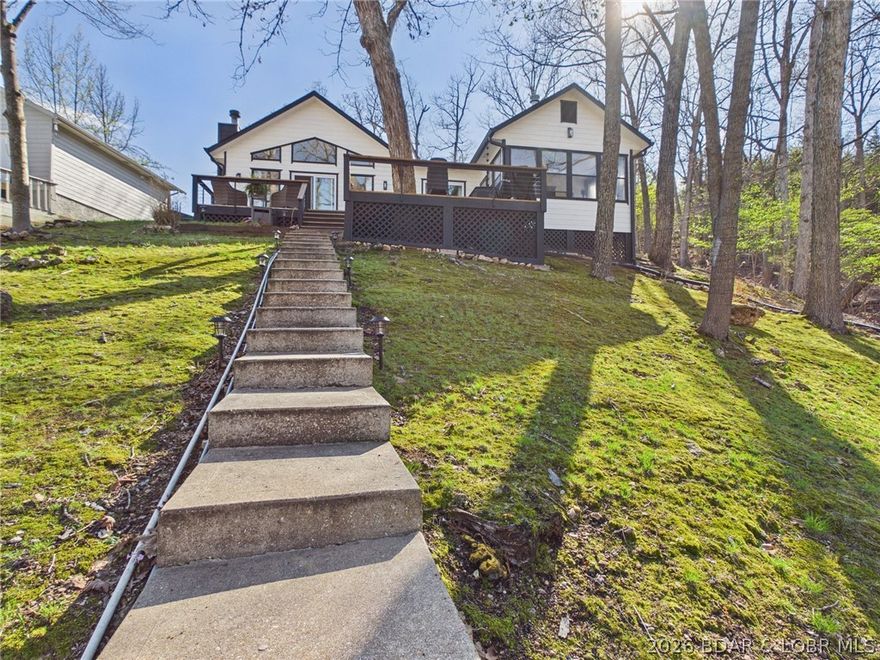 Turnkey lake opportunity in a prime 8MM location! Tucked in a deep-water cove with quick access to the lake’s most popular waterfront bars and attractions, this property is ideal for investors, short-term rentals, or a personal getaway. The dock features updated electrical, a 10x40 slip, swim platform, and WetSteps—ready for immediate use.  Enjoy low-maintenance lake living with a moss-covered yard and multiple outdoor spaces, including a martini deck and a two-tier deck overlooking the cove. Inside, the home offers a bright, clean interior with vaulted ceilings, open-concept living, and updated kitchen appliances with a stylish backsplash. Being sold turnkey, most furnishings and items convey for a seamless transition.  The primary suite includes two closets and private access to a 3-season room—perfect for relaxing or working from home. Heated floors throughout much of the home and a fireplace add comfort and efficiency year-round. A detached 2-car garage with storage and ample parking complete the package.