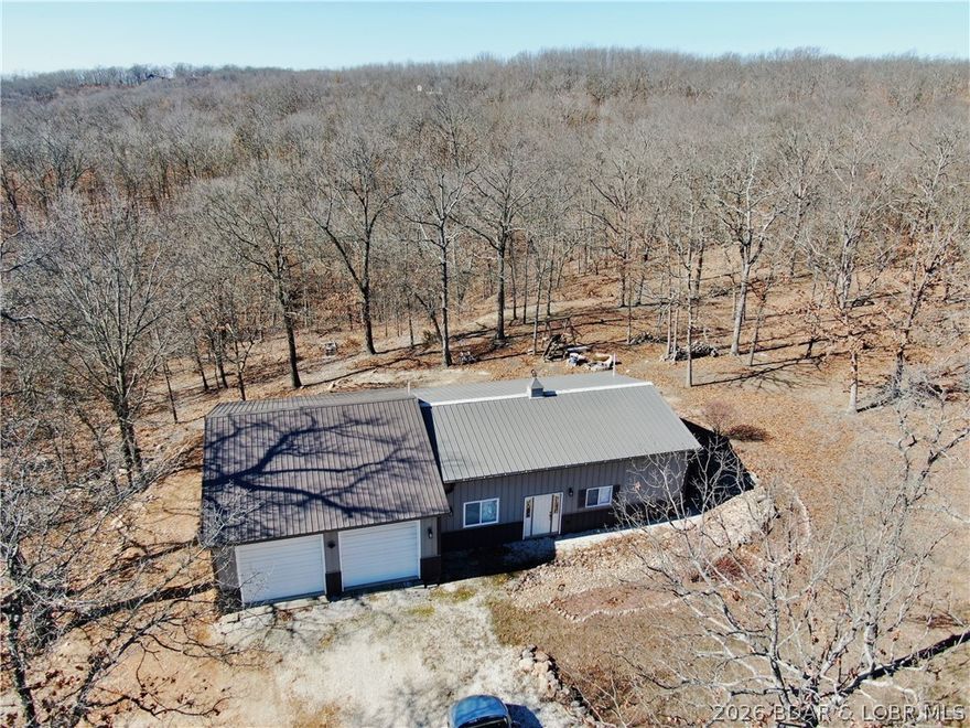 Nestled on 6.1 private acres, this exceptional 2 bed 2 1/2 bath shouse offers the perfect blend of comfortable living and functional space in a peaceful Camdenton setting. This property is ideal for those seeking room to spread out, enjoy privacy, or accommodate hobbies and recreational equipment. The open living area creates a welcoming atmosphere, connecting the kitchen and main living space for easy everyday living and entertaining. A standout feature of this property is the drive-through garage, providing exceptional accessibility and functionality. Whether you need space for vehicles, boats, ATVs, equipment, or workshop use, the pass-through design allows for effortless entry and exit, a rare and highly desirable feature for hobbyists and outdoor enthusiasts. The property offers ample room for recreation, expansion, or simply enjoying the tranquility of the surrounding landscape. With a balance of residential comfort and shop functionality, this shouse is perfectly suited for those seeking a weekend retreat, or full-time residence with space to grow. If you’re looking for acreage and privacy, here is your opportunity to own a property that offers an impressive package.