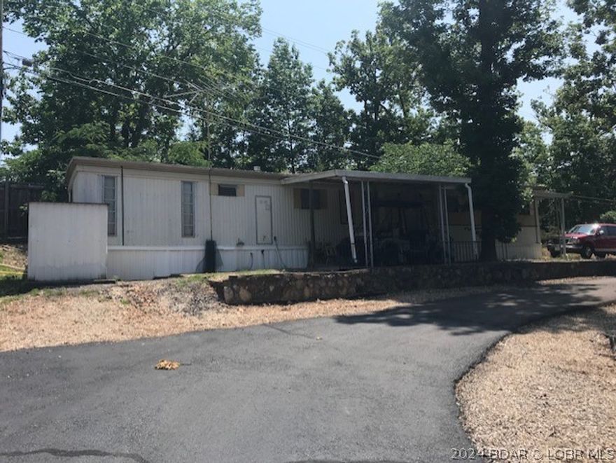 HUGE PRICE IMPROVEMENT!!  Want your own vacation home at Lake of the Ozarks for $15,000?  Here is a 3 BR/2 bath mobile home in a desired area of the lake.  Located at the 11MM right across from the Shawnee Bend public Boat Ramp.  Home is furnished and ready to enjoy life at the lake with central AC and heat.  The home could use some updating but this home is structurally sound.  Covered porch area the overlooks the lake.  There is even a community pool and your $850 monthly lot rent includes a 9x24 covered boat slip, water, trash, road and part septic.  This home won't last long at this price so hurry and set an appointment to see today!  Only parttime occupancy and no rentals per park rules.