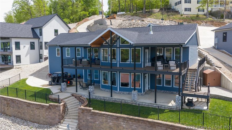 Tucked into a coveted 4MM Gravois arm setting, this standout lakefront retreat delivers the best of both worlds. Cove protection paired with a massive, wide-open view. With 120’ of lake front and over 1,500 sq ft of covered outdoor space, this home is built for long lake days and fun nights. The dock is next-level, featuring a full bar, TV, refrigerator, freshwater shower, and fish cleaning station… ready for everything from sunrise fishing to sunset cocktails. Inside, quality craftsmanship shines with Amish-made cabinetry, a hidden pantry, custom lighting, unique trim and walls of glass that keep the lake in sight from nearly every room. The kitchen is dialed in for both function and style with a coffee bar, pot filler, and under-cabinet lighting, while smart home technology is seamlessly integrated with Alexa-controlled lighting, whole-home Wi-Fi, and security system. Car enthusiasts will love the oversized 3-car garage with 10,000 lb lift, and the additional finished building offers incredible flexibility. Currently a wood shop with full bath, plus a bedroom and half bath above. This home isn’t just a place to live, it’s a place to experience the lake the way it was meant to be!