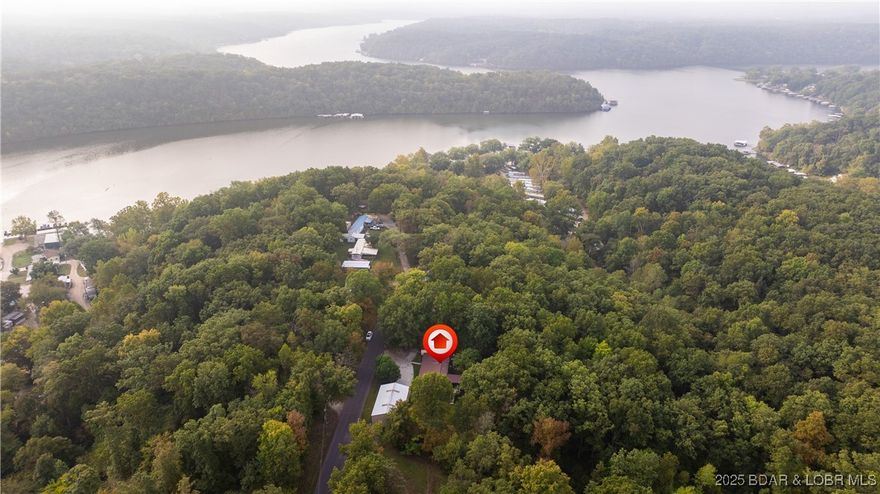 AFFORDABLE COUNTRY CHARM CLOSE TO THE LAKE! This peaceful retreat sits less than a mile from the Gravois Arm of the Lake of the Ozarks and offers the perfect mix of comfort, privacy and functionality. The incredible 60x30 shop is a dream setup with concrete floors, water, its own electrical panel and 2 large sliding garage doors making it ideal for a workshop, RV or boat storage, or the ultimate Man Cave/She Shed. The property backs up to over a 100 acres of undeveloped woodlands, providing abundant wildlife and incredibly peaceful privacy. Enjoy watching deer and turkeys play in your backyard from the comfort of your screened-in back porch or the shaded backyard. Inside, the flexible layout features multiple living spaces, and one additional room which could easily serve as a large third bedroom. The location is hard to beat as it's just 15 minutes to Laurie or Versailles with paved roads all the way. Whether you’re looking for a full-time residence or a weekend retreat near the lake, this property offers the space, serenity and setting to make it your own relaxing retreat.