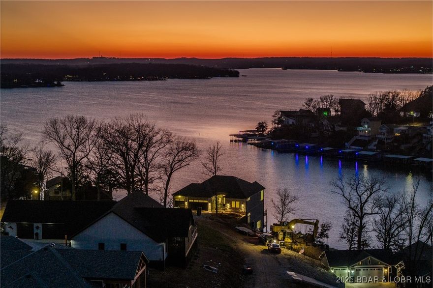 Experience unmatched luxury in this stunning brand new McQueen Homes masterpiece, perfectly positioned on 175 feet of pristine Lake of the Ozarks shoreline with an absolutely amazing view. Overbuilt for longevity and comfort, this home features 13.5 ' ceilings, 400 AMP service, 2-50 gallon hot water heaters, Pella windows, an 18 SEER/94% high-efficiency heat pump, gorgeous beams, floating shelves w/subtle LED lighting, shiplap accents, custom one-inch cabinetry w/soft-close drawers, over & under cabinet lighting. The gourmet kitchen showcases Café appliances, gas range, double ovens and a spacious walk-in pantry. Flow right into your lakeside dining area with breathtaking scenery. The luxurious master suite offers a custom walk-in shower, soaking tub with an eagle’s-eye view & custom pull-down closet built-ins. With 4 bedrooms, 4 full baths, a large bonus/workout room, two laundry rooms, and a wine cellar with wine cooler, the layout is ideal for full-time or vacation living. The lower-level wet bar features accordion windows opening to the outdoor deck, perfect for lakeside cocktails near the sparkling swimming pool and a view for miles. This is lakefront living at its finest.