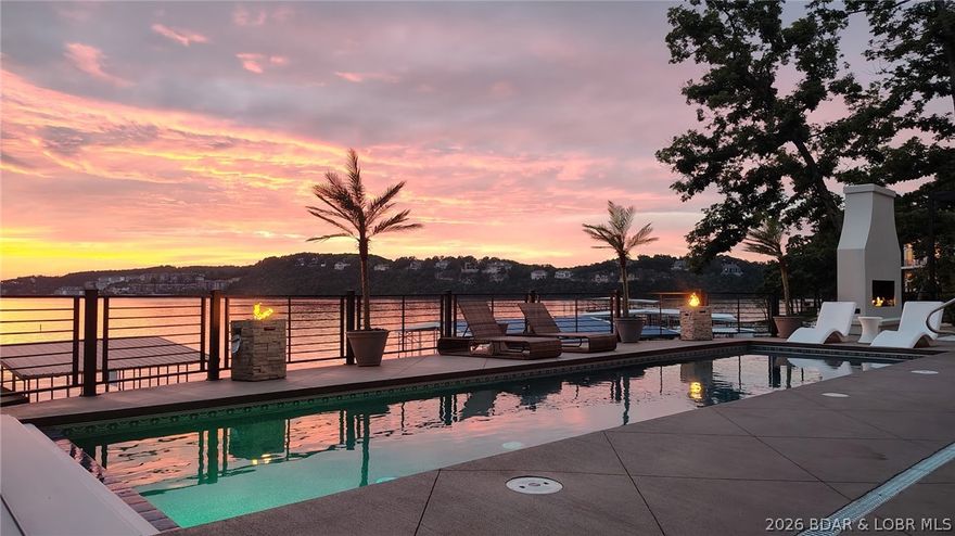 THIS is what luxury new construction at Lake of the Ozarks should look like. Perfectly positioned in a cove with main channel views at the Osage 15MM in the prestigious Porto Cima community, this custom lakeside estate delivers true resort-style living. The outdoor space is stunning—featuring a heated gunite pool w/ tanning shelf, stamped concrete decking, see-through gas fireplace & covered cabana with grill station; all surrounded by extensive, professionally designed landscaping with illuminated stonework along the shoreline creating a striking floating effect. Inside, the living room showcases 16' high ceilings w/ an expansive quad-panel stacking glass door system, seamlessly blending indoor & outdoor living. The kitchen impresses w/ layered accent lighting throughout, custom cabinetry, quartz countertops, warming drawer, pot filler & even double dishwashers! The lower level includes a 6-sided concrete safe room ideal for a bunker, wine cellar or gun room. Additional highlights FULLY furnished, include epoxy garage floor & pool bath floor, gentle driveway + additional parking. Premier location by land & water near golf, dining, entertainment, shopping & quick highway access.