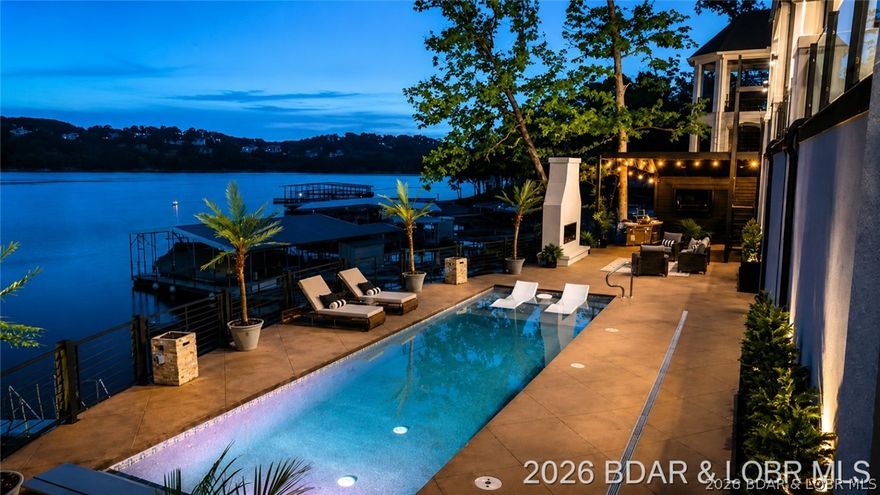 THIS is what luxury new construction at Lake of the Ozarks should look like. Perfectly positioned in a cove with main channel views at the Osage 15MM in the prestigious Porto Cima community, this custom lakeside estate delivers true resort-style living. The outdoor space is stunning—featuring a heated gunite pool w/ tanning shelf, stamped concrete decking, see-through gas fireplace & covered cabana with grill station; all surrounded by extensive, professionally designed landscaping with illuminated stonework along the shoreline creating a striking floating effect. Inside, the living room showcases 16' high ceilings w/ an expansive quad-panel stacking glass door system, seamlessly blending indoor & outdoor living. The kitchen impresses w/ layered accent lighting throughout, custom cabinetry, quartz countertops, warming drawer, pot filler & even double dishwashers! The lower level includes a 6-sided concrete safe room ideal for a bunker, wine cellar or gun room. Additional highlights FULLY furnished, include epoxy garage floor & pool bath floor, gentle driveway + additional parking. Premier location by land & water near golf, dining, entertainment, shopping & quick highway access.