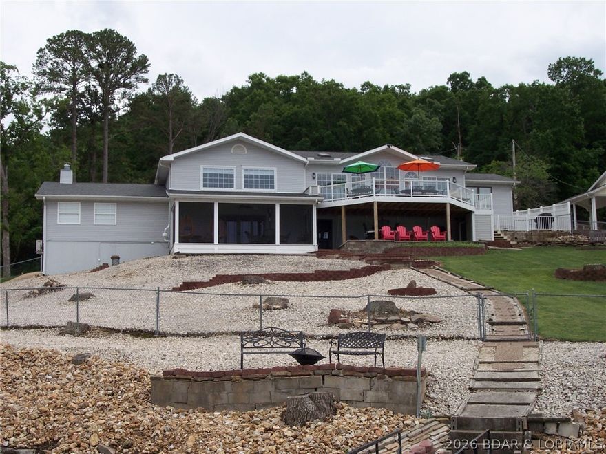 Incredible main channel views of 31MM Lake of the Ozarks with cove location!  1.28 acres with 180' deep water lakefront.  4654 SQFT 4 BR/3 full bath home (4th BR non-conforming) includes upper and lower level kitchens and laundry.  There is also a huge family room/game room.  Sunroom with lots of west facing glass off of kitchen and dining area offer those amazing lake views and a huge deck just off of the sunroom makes for a perfect area for family.  Under the deck is a screened porch with more lakefront views.  Deep two car attached garage with plenty of storage area.  Back yard is completely fenced in for pets or little ones.  2 storage rooms under home for water toys, etc.  Home has been recently remodeled and shows pride of ownership.  Dock is a 2 well covered dock with 2 boat lifts. Slip sizes are 10x27 and 10x23.  Years invested in making this dock a great fishing spot. Natural stone seawall protects the shoreline of this beautiful lakefront home.  Newer HVAC system installed in the last 2 years.  Tons of parking for guests or large family.  Home is located on county-maintained asphalt road.  This home will not disappoint and is a pleasure to view!