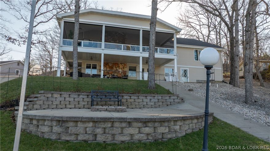 This exquisitely reimagined lakefront retreat offers 4 bedrooms, w/the option to convert the office into a 5th bunk room, along w/3 baths & spacious 2 car garage. It sits gracefully on a gentle cove lot w/no exterior steps, capturing sweeping main channel views & providing an abundance of space designed for elevated entertaining & relaxation. Whether you’re unwinding in one of the 2 expansive great/family rooms w/fireplaces or retreating to the lakeside primary suite w/captivating water views, every corner of this home is designed to inspire. The primary suite features a fully updated en suite, walk-in closet & convenient in-suite laundry area. Guests, renters or loved ones will feel right at home in the generously sized bedrooms. The thoughtfully appointed luxury kitchen invites culinary creativity & flows seamlessly into the oversized screened-in porch, complete w/infrared heat & blinds—an idyllic setting for morning coffee or sunset gatherings where panoramic main channel views take center stage. Down by the water, the private dock is equally impressive, featuring 2 boat slips, swim platform, ample storage & even a private boat ramp—perfect for embracing the full lake life.