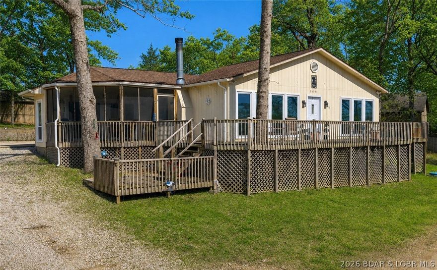Wake up to beautiful lake views in this main level living home, situated in a peaceful neighborhood. This 3bed/2bath home includes a new HVAC that was just put in and recently hooked up central sewer system! Exterior features include multiple deck spaces (open & covered), an ideal screened-in deck, gentle topography, abundant parking & sits on 2 lots. Oversized 2-car garage is a heated & cooled pull-through—super convenient! Inside offers a spacious living room with LVP flooring & gas fireplace, large kitchen with ample cabinet/counter space, unique ceiling detail above the island, pantry & a light-filled sunroom for seamless indoor/outdoor living. Primary suite includes lake views, deck access, walk-in closet, walk-in shower & soaking tub. Energy efficient with heat pump & attic fan—avg electric under $100! Large crawlspace for easy access & storage. Boat ramp just a short walk away; located at the 1.5MM of the Gravois by water. Seller is offering a $5,000 concession on exterior painting upon acceptable offer!