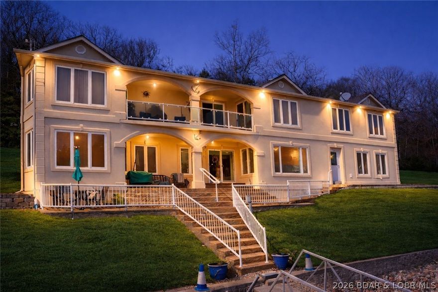 Magnificent 5BR/3BA lakefront estate offering 379’ of shoreline and 5 acres of privacy at the 3MM of the Gravois Arm. Tucked into a quiet cove with wraparound frontage, this property feels like your own private oasis with deep water year-round and just a few easy steps to the private dock. The updated kitchen features new cabinetry, granite countertops, stainless steel appliances, and a stylish backsplash. The open concept layout flows seamlessly into the bar area and inviting family room with cozy fireplace and custom built-ins—perfect for gathering and entertaining. All five bedrooms are located upstairs, including three with access to the upper terrace showcasing peaceful lake views. A covered patio provides the ideal setting for outdoor dining and relaxing. Ample parking plus a 2-car attached garage. The garage loft includes rough-in plumbing and electrical—ready for a future bunk house or guest suite. Close to waterfront restaurants, gas docks, and lake attractions. Exceptional location, acreage, and shoreline—lake living at its finest!