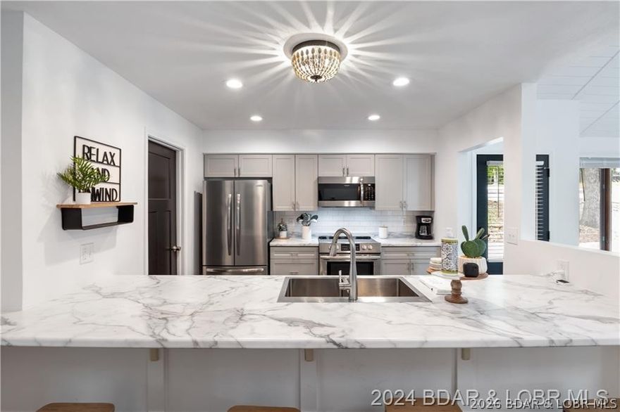 You will love this beautifully remodeled, partially furnished home located in the wonderful Four Seasons area. The triple pane sliding door in the living room allows a beautiful, expanded view making the outdoor views even better. In addition, you can enjoy the views from the 3 lakeside bedrooms. This charming 3-bedroom, 2.5-bathroom home features open floor plan, four seasons room, and a two-car garage, situated on a gentle sloping lakefront lot with cove protection. The living/dining areas have a vaulted shiplap ceiling enhanced by skylights, and a striking black shiplap gas fireplace wall. The interior showcases newer flooring, custom cabinetry with soft close doors/drawers, stainless steel appliances, stainless steel sink, and black three-panel interior doors and handles. Each of the three bathrooms is equipped with newer vanities. There is also a four-season room with new custom shades. Spacious upper/lower decks have black aluminum handrails. There’s a martini deck at water’s edge to enjoy. This property includes a dock boat and lift perfect for a ski boat, tri-toon, or wakeboard boat. The circular driveway provides ample parking space. Brand New Septic!