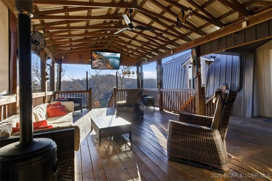 Lake living doesn’t have to come with a lakefront price tag, and this home in Rainy Creek Cove at the 60 MM proves it—offering lifestyle, dock potential, and investment opportunities! A recorded easement in front of the home to the shoreline is in place and approved by Ameren for installation of a private dock up to 30 ft wide with a 40ft ramp! This 3 bedroom, 2.5 bath lake home is designed for entertaining, with a huge kitchen island and an amazing covered deck with tons of seating, sun shades, TV, fridge, games, and an outstanding lake view! Oversized 2-car garage, plenty of front and back parking, PLUS a 35-amp RV hookup with water/ sewer make hosting family and guests easy. Lots of updates such as a metal roof installed (2023), updated bathrooms, and more! Located in a large, calm cove known for great fishing, swimming, kayaking, paddle boarding, etc, this move-in-ready home comes mostly turnkey with a security and sound system already in place. No hoa, nightly rentals are allowed, and less than half a mile of gravel. This is the kind of lake house where weekends turn into traditions, summer nights stretch longer, and everyone ends up on the deck together!