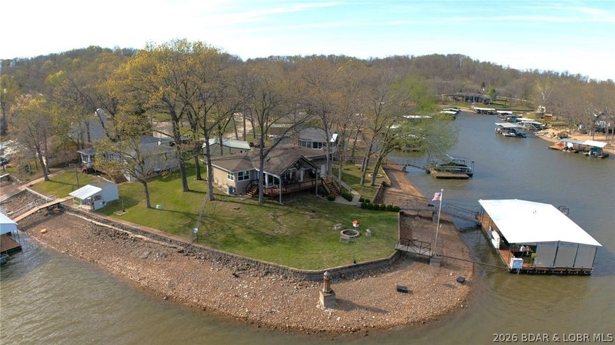 Lakefront living at its finest in this stunning waterfront ranch home, perfectly positioned on year-round deep water with panoramic views of the Lake of the Ozarks. Sunlight pours into every room, offering breathtaking lake vistas and unforgettable sunsets from nearly every angle. Beautifully maintained, move-in ready featuring two spacious bedrooms and two full bathrooms, with an open-concept floor plan designed for effortless entertaining. The four-seasons sunroom invites you to start your day with morning coffee as you watch the sun rise over the water in this eastward-facing retreat. Enjoy the ultimate in outdoor living with a wrap-around deck, ideal for gatherings or peaceful evenings overlooking the lake. Boating enthusiasts will appreciate the three-slip covered dock, complete with three lifts, a swim platform, and a diving board—perfect for summer fun with family and friends. Storage and flexibility are unmatched, with both attached and detached garages, as well as a charming “she shed” for all your hobbies and gear. Most furnishings are included, making this an easy turnkey opportunity—just bring your suitcase and start enjoying lake life right away. Priced at $659,900