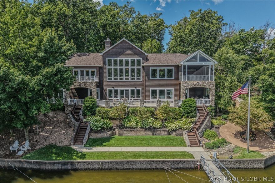 Positioned within an exclusive gated estate situated on 10.7 fully fenced acres in Osage Beach, this exceptional lakefront residence offers rare privacy and sweeping views of untouched state park shoreline. Encompassing 7,500 sq ft with 850’ of shoreline, it delivers a refined lake lifestyle with an impressive private dock. A grand entry showcases soaring vaulted beam ceilings and walls of glass capturing breathtaking water views. The chef’s kitchen flows seamlessly into expansive living areas and a screened porch with commercial-grade exhaust for year-round entertaining. Featuring 6 bedrooms, a private office/den, 6 full baths, and 2 half baths, the home is anchored by a luxurious primary suite with steam shower and oversized boutique-style closet with island. The walkout lower level offers a theater, bar, and game area, with additional bar service on the main level and dock. The dock includes a 16x48 slip with 30,000 lb lift, 12x30 slip with lift, and double PWC slip with lift. Additional amenities include attached and detached 3-car garages, climate-controlled gym, and RV pad with electric. Pre-listing inspected with a one-year home warranty included.