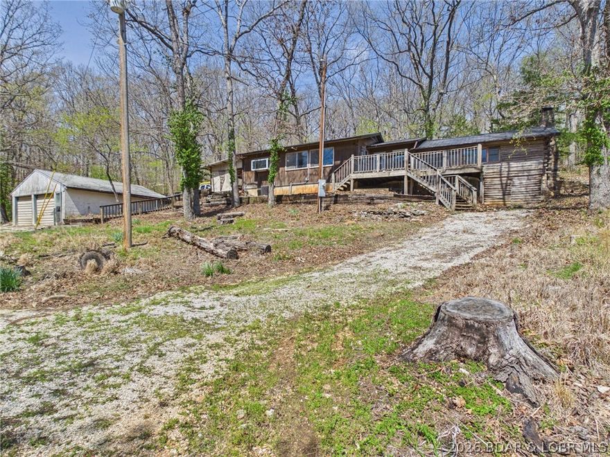 Trade the subdivision for the sound of silence at this 11± acre wooded "basecamp" in Stover. The heart of the home is a true stacked-log cabin—providing a rugged, authentic Ozark character you simply cannot recreate—now expanded into a functional 1,300+ sq ft, 2-bed, 1-bath residence. Best of all? You can work from the woods with high-speed internet available.

Surrounded by heavy timber on three sides, this property is a outdoorsman's  dream. The detached 2-car garage is ready for ATVs and lake toys, while the terrain features a natural backstop area perfect for a private shooting range or target practice. With frequent deer and turkey sightings, you can hunt or wildlife-watch directly from your covered concrete patio.

Enjoy unmatched seclusion just minutes from the marina and lakefront amenities. Equipped with a new metal roof (2025), this property is built for the buyer who wants a tactical weekend getaway or a primary residence with zero neighbors in sight. Bring your tools and a little sweat equity to finish out this standout Ozark classic.