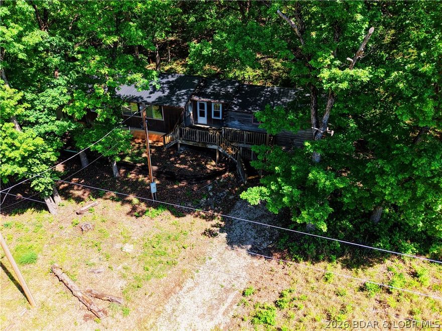 Trade the subdivision for the sound of silence at this 11± acre wooded "basecamp" in Stover. The heart of the home is a true stacked-log cabin—providing a rugged, authentic Ozark character you simply cannot recreate—now expanded into a functional 1,300+ sq ft, 2-bed, 1-bath residence. Best of all? You can work from the woods with high-speed internet available.

Surrounded by heavy timber on three sides, this property is a outdoorsman's  dream. The detached 2-car garage is ready for ATVs and lake toys, while the terrain features a natural backstop area perfect for a private shooting range or target practice. With frequent deer and turkey sightings, you can hunt or wildlife-watch directly from your covered concrete patio.

Enjoy unmatched seclusion just minutes from the marina and lakefront amenities. Equipped with a new metal roof (2025), this property is built for the buyer who wants a tactical weekend getaway or a primary residence with zero neighbors in sight. Bring your tools and a little sweat equity to finish out this standout Ozark classic.