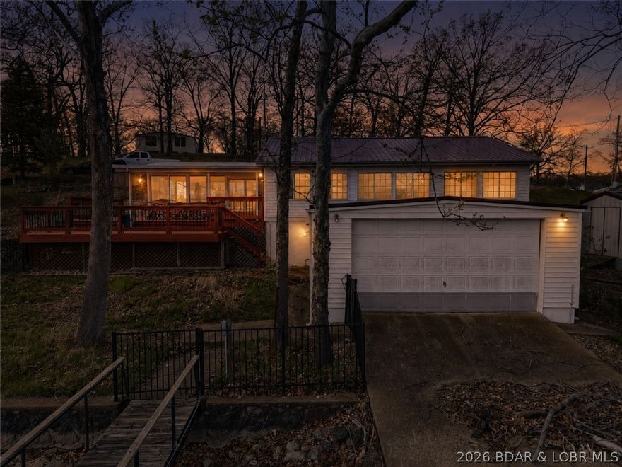 Experience lake living in one of the most sought-after coves at the Lake of the Ozarks! This beautifully updated 3-bedroom, 2-bath waterfront home offers 105 feet of shoreline in Mill Creek Cove. Just around the corner, Lake Burger provides dining, entertainment, and a lazy river experience. Outdoor amenities make this property stand out, including a 20x24 swim platform with custom ladder and high dive, established crappie beds for dockside fishing, and a covered two-well dock featuring two 10x24 slips plus a boat lift. The large lakeside deck and inviting sun porch create the perfect setting for entertaining or unwinding while enjoying panoramic water views. Inside, the home has been tastefully updated and comes partially furnished — just bring your beds and bedding. The level fenced yard is ideal for pets, games, and family gatherings. An unfinished boathouse offers excellent storage or future expansion potential for added living space. Owners also enjoy access to Camp Sharon amenities including a boat ramp, tennis court, basketball court, and playground. Don’t miss this opportunity to own a turnkey waterfront retreat in one of the lake’s most desirable coves!