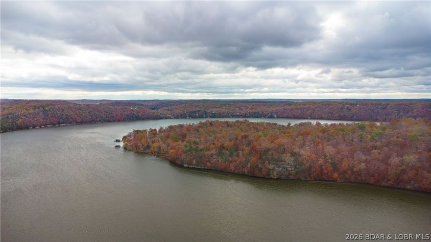 An extraordinary development opportunity in a lake area gated community. This offering includes 10 parcels totaling 154+ acres of beautifully wooded landscape with diverse terrain, ideal for creating a luxury lakefront retreat, or thoughtfully designed residential development. With over 6,000 feet of shoreline on Lake of the Ozarks, the property delivers immense waterfront potential & breathtaking views. Infrastructure is in place to jumpstart your vision-electric, waste treatment, and a water well system capable of servicing up to 75 homes. Utilities already available to 8 lots. A 100x50 barn equipped with electric, water, & sewer provides immediate functionality for storage, office space, staging, or on-site operations. To make this opportunity even more turnkey, essential development equipment: John Deere backhoe, John Deere 240 skid steer, Kubota LA805 L4060 tractor with loader and brush hog are included. Whether you envision an investment subdivision, or signature lakefront community, this property offers the scale, infrastructure, and location to bring it to life. Opportunities of this magnitude along Lake of the Ozarks are rare—explore the possibilities today.