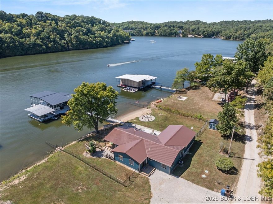 LAKEFRONT HOME on a FLAT LOT in Barnett,MM6-Gravois Arm! Welcome to your dream lake retreat! This 3-bed, 2-bath ranch home is brand new from the foundation up in 2020 & is true 1-level living w/ all the luxury features of new construction. This property is a rare gem on a gentle lot w/ over 100 feet of shoreline. Step inside to find an open-concept layout w/ vaulted ceilings, rustic wood beam accents, & a cozy stone fireplace. The heart of the home is the stunning kitchen, featuring custom cabinetry w/ crown molding, soft-close drawers & doors, stainless steel appliances, & a large center island. The outdoor living space is a true oasis w/ a hot tub, fire pit, sandy beach, Pelican Perch tree house, & fenced yard. The incredible 3-well dock includes: 18x50 slip, 12x30 slip, 10x28 slip, 2 PWC lifts, Wet steps, high-dive platform, & a spacious swim area. Additional highlights include: Metal roof, Covered & open concrete patios, & Bonus second-tier lot w/ plenty of space to build a garage. Just a short boat ride to Coconuts & Jolly Rogers, this location offers the perfect mix of tranquility & convenience. Clean, modern, & move-in ready – this is lake living at its finest.