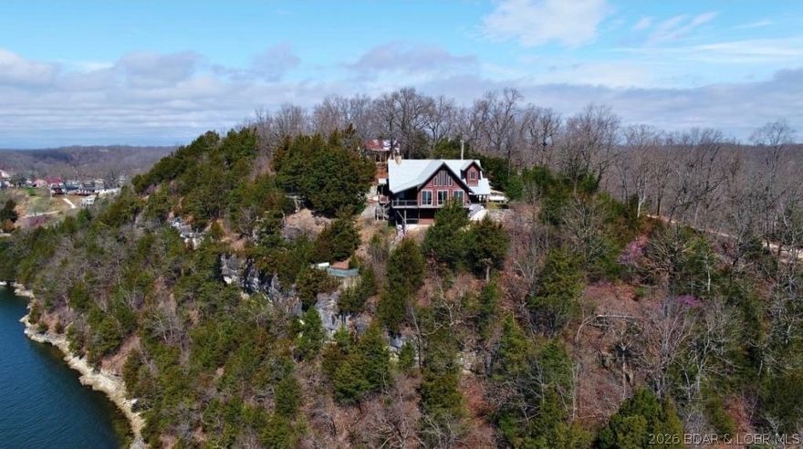 A VIEW FOR MILES!
This one-of-a-kind custom log home showcases stunning craftsmanship, featuring hand-selected Cypress logs sourced from Georgia and rich cherry wood flooring throughout. Soaring ceilings with exposed wood beams and a dramatic wall of windows flood the home with natural light while perfectly framing the breathtaking panoramic lake views. Open-concept floor plan flows seamlessly into a spacious living area, a beautiful stone wood-burning fireplace. Step outside onto expansive decks, complete with a hot tub and a signature martini deck—ideal for relaxing or hosting guests while taking in the scenery. The home offers 2 bedrooms plus an open loft (perfect for a 3rd bedroom or additional living space), along with a large 2-car garage already plumbed for a future bathroom. Additional features include solid wood custom entry doors, iron railings, granite countertops, and a durable composite slate roof with a 50-year warranty. Two gated entrances, the property offers ample parking, and exceptional privacy.
Truly one of a kind. 

*Tenant Occupied. Photo provided prior to tenant occupancy. Adjacent 2.3 acres being sold separately.