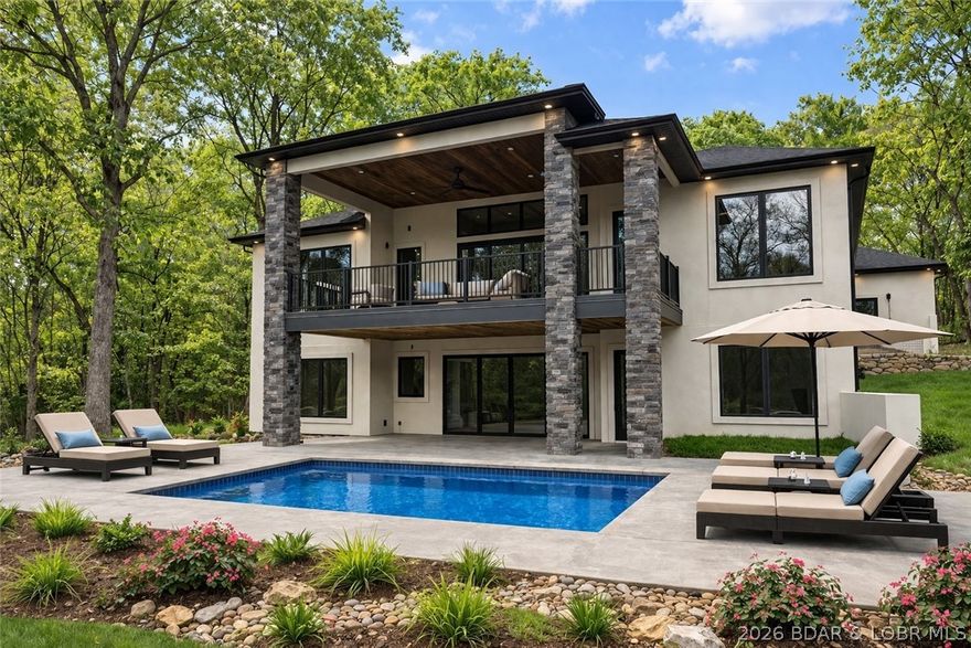 Welcome to your new modern retreat in Porto Cima. This stunning 4 bed, 3.5 bath home features three fireplaces, striking architectural details, and an open layout perfect for entertaining. The exterior makes a statement with sleek glass 8x10 garage doors and an extended 80-ft concrete driveway. Inside, you’ll find a seamless flow between living spaces, designer finishes, and warm gathering areas centered around multiple fireplaces. An additional lot provides extra privacy, room to expand, or space for a future pool with the hook ups already available. The impressive 80-foot concrete driveway offers ample parking and a grand approach to the home. There is a seperate exterior side entry to large crawl space storage and HVAC. A rare opportunity to own a fresh, modern build in one of the Lake’s most sought-after communities. Rendering of an optional pool in pictures.