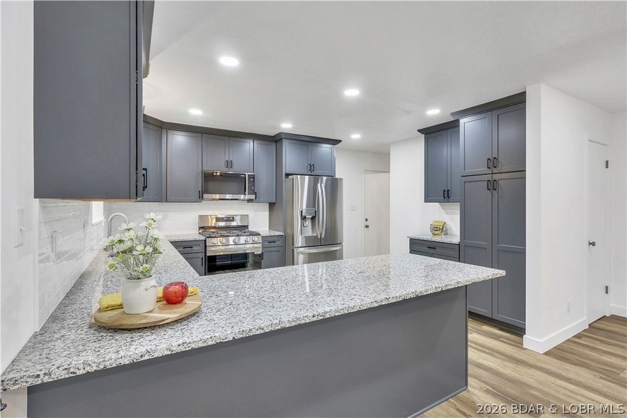 1960s brick beauty in Eldon city limits—neighborhood heart, fully reborn.Can you say NEW, NEW NEW! This is a MUST SEE! Outside you'll find New metal roof, gutters, fascia, landscaping, covered front porch, backyard patio. Inside Three beds, with one en-suite, two baths (walk-in shower), stainless LG kitchen appliances, gleaming granite countertops, crisp cabinetry, gas range, recessed can lighting, new fan/lighting that whispers cool air and glows just right. Cozy white-stone fireplace with electric insert. Newer windows throughout, bright, energy-smart, no drafts. 1800 sqft of pristine living, new luxury vinyl plank flooring —plus 1800 sqft of blank-canvas basement: half-bath rough-in, laundry, workshop. Feel the charm. Stunning & priced sharp!