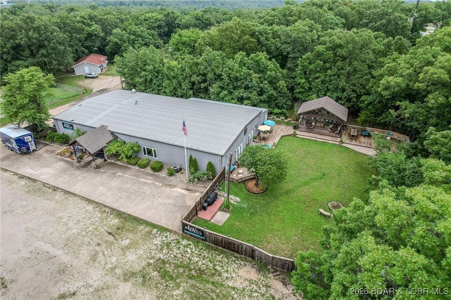 Located in Osage Beach, ZONED I-1, This Wonderful COMMERCIAL OPPORTUNITY is Available. 5,600 SqFt Metal/Steel General Purpose Build’g in Nearly Excellent Condition on 1.38 FLAT Acres. Covered Entry w/Double Glass Entry Doors, Huge (Approx 3,400 Sq Ft) Open Interior Hall, Beautifully Decorated. Could easily be divided into Priv. Offices, Smaller Areas, Class Rms or used for Large Show Room. Full Comm’l Kitchen, Glamorously Remodeled His & Her Baths, Beautifully Maintained Outdoor Fenced-in Flat & Grassy Landscaped COURT YARD w/16'x 24' Covered Stage Equipped for Entertainment w/Lighting & Sound. Large Outdoor Deck Areas, Fire Pit Area, Huge Grassy Area & More. Lovely Comm’ly Equiped Bar. Flat Park’g for 100+ Cars. Security & Sound Systems. CURRENT USE is Dance Club & Event Center w/200 person capacity. Tall Ceilings & Plenty of Space to Make Your Own. Lrg Storage Area. Sellers will remove the Dance Floor & some other Dance Features. Event Inventory can be Purchased Separately. Private Well & City Sewer. Near the Airport & YMCA. 500 feet off the HIGHWAY. Building & Land Being Sold. All Newer Lighting, Fixtures & Panels Stay. Ideal for So Many Types of Business'. Must see Virtual Tour