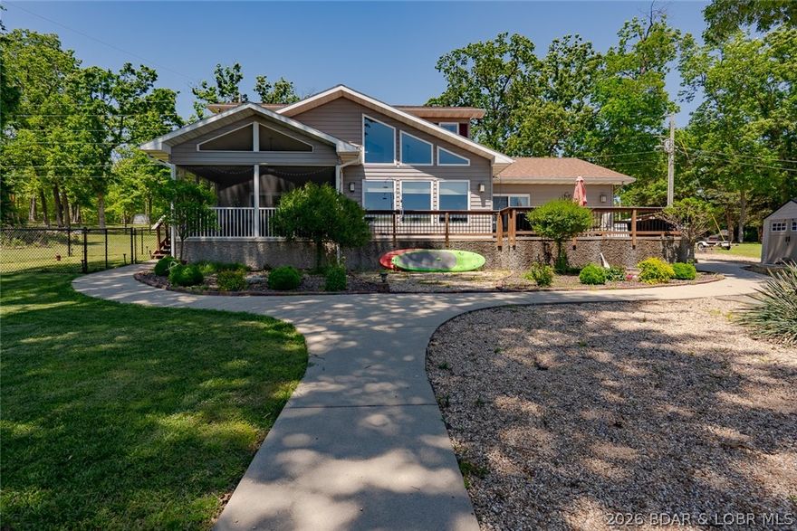 Stop the car & the boat! This stunning lakefront home is the perfect full-time residence or weekend getaway & truly checks all the boxes. Conveniently located w/ blacktop to the door & close to area amenities, this beautifully designed home offers a level driveway, 2-car garage & addit parking,Step inside to a wall of windows that offers lake views & vaulted living space. The gorgeous kitchen features granite countertops,stainless steel appliances, & flows seamlessly into the spacious dining area & great room ideal for entertaining Enjoy true main-level living w/ a spacious primary suite offering a walk-in closet & spa-like bath complete w/ double vanity & tiled walk-in shower. The screened porch provides the perfect place to relax and unwind. Main level also includes a half bath and full laundry room. The open patio is perfect for grilling & outdoor gatherings. Outside the extremely gentle lakefront features a beautiful lawn,firepit area along the shoreline, & fenced area for pets. Upstairs offers two additional bedrooms and a full bath with double vanity. The 3-well dock is tucked into a protected cove while still offering fantastic main channel views. Brand new roof in 2024.