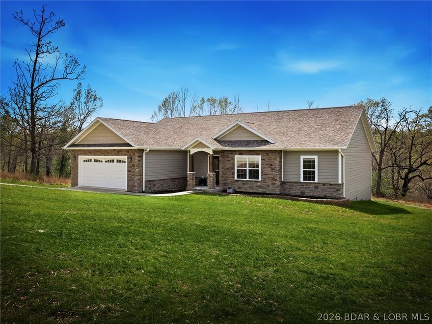 Lake living starts here! Nestled within the gated community of Buckingham Estates, 19 Lancelot Court offers a rare combination of new construction, stylish finishes, and an exceptional lineup of Lake of the Ozarks amenities. 
This 4-bedroom, 3-bath home welcomes you with a bright, open layout, an oversized kitchen island with granite countertops, maple soft-close cabinetry, high ceilings, and luxury vinyl flooring that ties the main living areas together beautifully. The primary suite offers a spacious retreat, complete with a walk-in closet and custom shower. Additional bedrooms and baths provide plenty of room for family, guests, or entertaining. Outside, the covered Trex deck opens to a backdrop of rolling hills and trees, creating the feeling of a private wooded escape, with Camdenton dining and shopping just minutes away. 
Owners here enjoy access to the amenities of both Shores of Camelot and Camelot Estates, including three swimming pools, leasable dock slips, the yacht club, lodge, horse stables, and fishing shack. Whether your perfect day is out on the water, lounging by the pool, or simply enjoying peaceful surroundings, this property puts it all within reach.