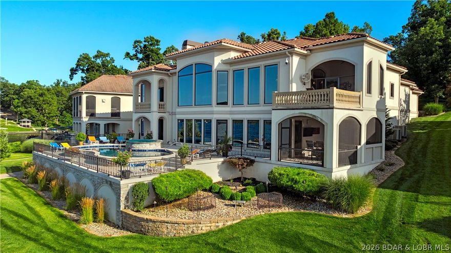 Arrive with quiet distinction through a gated, gentle private drive—remarkably refined for Lake of the Ozarks—leading to this exceptional estate in Porto Cima, one of luxury Shawnee Bend’s most exclusive enclaves. Inside, uncompromising craftsmanship and bespoke finishes define every space, while dramatic walls of glass capture sweeping, miles-long Main Channel views. Thoughtfully reimagined, the residence offers new windows, rich flooring, plush carpeting, and timeless architectural detail throughout. The chef’s kitchen is a statement of elegance, featuring striking granite, custom cabinetry, designer tile, and professional-grade appliances. The primary suite rivals a five-star spa with a jetted soaking tub, expansive tiled shower, sauna, and an extraordinary custom wardrobe. Designed for elevated entertaining, the lower level showcases a grand lounge, sophisticated bar, billiards, private cinema, and elevator-ready space. Outdoors, indulge in a screened culinary pavilion, resort-caliber pool, and spa at the shoreline. A brand-new dock and breakwaters built by the lake's most exciting new manufacturer, US Boat Dock LLC, delivering in June, completes this legacy-caliber offering.