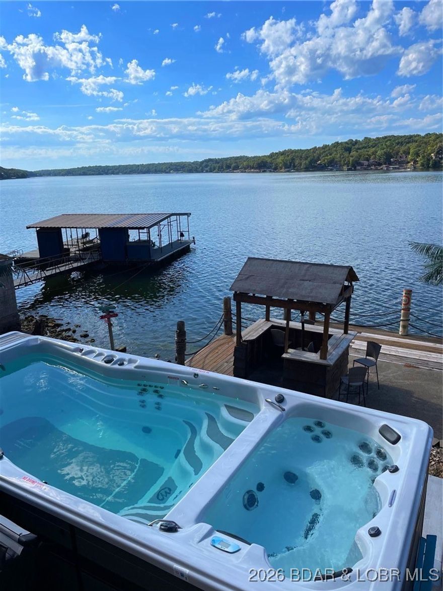 This home is Ready for Summer Fun! Boatiing, Swimming, Fishing, Relaxing... this place has it covered! Home Offers breathtaking views of LOZ & unforgettable sunsets. Step outside onto the spacious decks to soak in the serene lakeside ambiance... perfect for entertaining family, friends and guests. Main Level features Open floorplan, main level living, a spacious kitchen w/plenty of cabinets & overhead lighting , Vaulted Ceiling, Nice size primary suite w/adjoining  bath complete with double vanity, oversized mirror & walk in shower w/frameless sliding glass doors and a second bedroom. Lower level features a Large Family Room, 3rd bedroom, versatile oversized bonus space with endless possibilities-could easily be converted into a 4th bedroom, bathroom w/lighted mirror & large storage area. Venture down to the lakefront & enjoy the Swim Spa (perfect year round ), relax on the martini deck w/bar area, Fish right from your dock or Launch your boat and head straight out to the lake! Located close to Waterfront Entertainment- Let's Go! PLUS Tons of parking w/room to add garage (entry door already in place) & 2 second tier lots included. INVESTORS - Perfect Property for Vacation Rental!