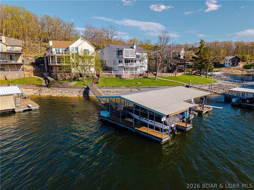 This exceptional waterfront property offers the perfect blend of panoramic views, cove protection & convenience featuring main-level living, a flat driveway & minimal steps to the 3-well dock. Designed for both comfort & entertaining, this spacious home offers 3 levels of living space & spectacular lake views from every floor. From the moment you step into the home you’ll be captivated by the vaulted ceilings & abundant natural light. The beautifully remodeled kitchen is a true highlight, featuring custom cabinetry & thoughtful design that blends style & functionality. The middle level offers a welcoming family room & 3 bedrooms, creating the perfect setup for family & friends. Retreat to the remodeled master bathroom where you’ll find a beautiful soaking tub, gorgeous tile details & stunning fixtures that create a spa-like atmosphere. Quality craftsmanship shines throughout with Masonite siding, Andersen windows & attention to detail at every turn. Outside, the dock is ready for lake days, complete with a slide & a diving board. Located at the 10 MM by water & just 15 minutes across the toll bridge, this remarkable property combines charm, functionality & unbeatable views.