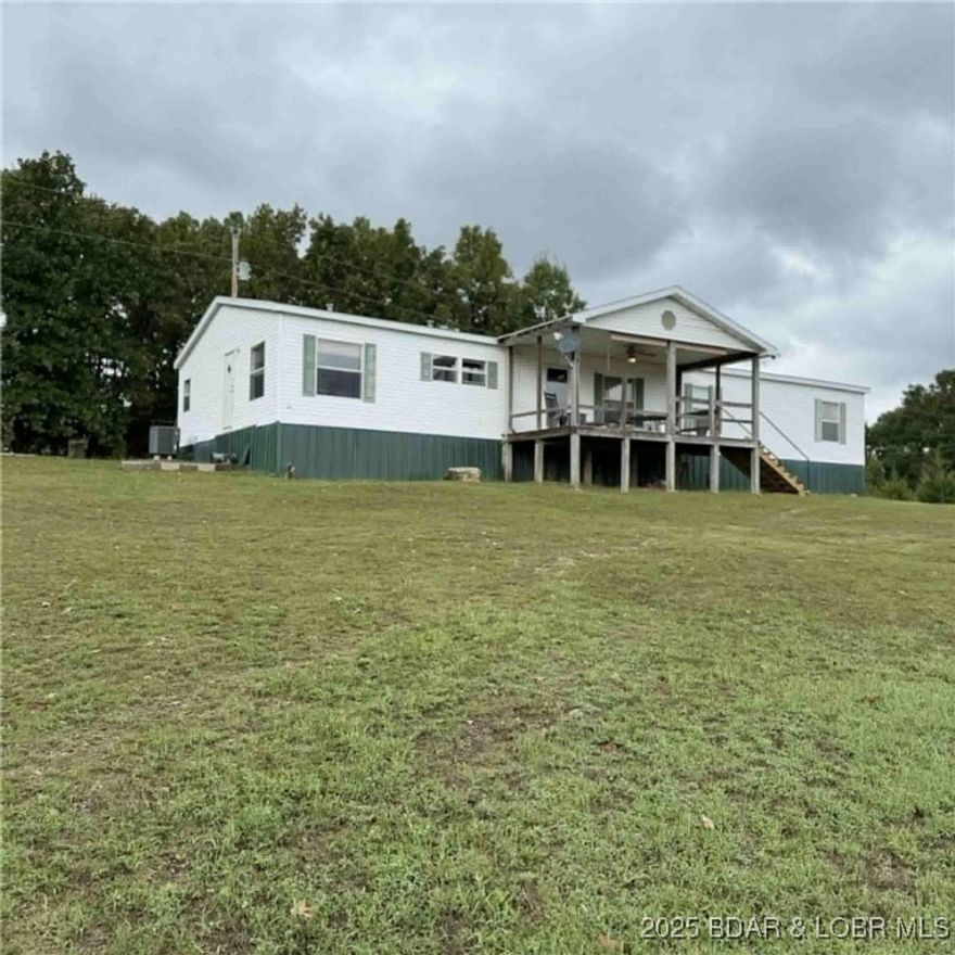 Escape to 20 acres of privacy and country living! This 2,040 sq. ft. manufactured home offers 5 bedrooms, 3 Baths, primary bedroom offer walk-in closet, soaking tub. This home has beautiful views overlooking open pasture, perfect for horses, goats, cows or chickens. A 30x40 barn with 5 horse stalls and a hay storage area makes this property ideal for livestock or hobby farming. The land is mostly wooded, attracting abundant wildlife including deer and turkeys for nature lovers.
Recent updates include a newer metal fence (2014) and a newer roof (2017). The home also features a wood-burning fireplace (not used in several years) that adds rustic charm. All this is located less than 20 minutes from Lake Ozark, giving you the perfect mix of seclusion and convenience.