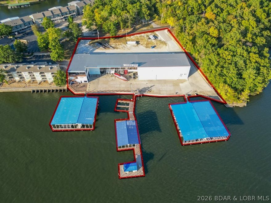 The Boardwalk, one of the most exciting commercial waterfront opportunities at Lake of the Ozarks! Located at the 26 MM directly beside Margaritaville, this 2.05 acre property sits in one of the lake’s busiest destinations with excellent access by land & water. Previously operated as a marina & dry storage facility, the site features an impressive steel-framed structure totaling appx. 30,000 sq ft, including an office space with incredible views. The main structure offers soaring ceiling heights with zoning allowing expansion up to 120 feet in height, creating exceptional potential. Existing infrastructure includes dry storage, 27 boat slips, and a fuel dock. The office building offers commercial bathrooms, storage areas, and a residential style condo unit, with plenty of parking. While the property has operated as a marina, additional value lies in its possibilities. The structure and location lend themselves to numerous concepts including a marina, waterfront restaurant, entertainment venue, pool bar, or other mixed-use developments. Commercial waterfront properties of this scale & location rarely become available at Lake of the Ozarks. Owner financing options may be considered.