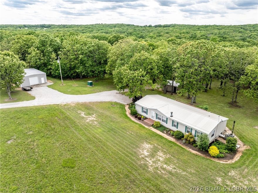 This meticulously maintained 3BD,2BA home sits quietly at the end of a long driveway on 74 beautiful acres. The care and attention given to this property are evident at every turn featuring a newer roof & gutters, newer windows & doors, dishwasher, water heater, along with carpet and laminate flooring throughout. A wood-burning fireplace anchors the living room. The spacious primary bedroom includes additional space ideal for an office, nursery, or sitting area. Step outside onto the expansive 12’x33’ deck-an ideal spot to relax and enjoy abundant wildlife. A Shelter Wood-burning outdoor furnace provides an efficient alternate heat source. Approx. 30 acres are used for hay production with the remaining in timber, offering excellent versatility for farming or recreation. A 30’x40’ insulated steel building with concrete floors, plus a former garage converted into pens for chickens and rabbits. The beautifully landscaped yard offers plenty of room for playsets, horseshoe pits, or open green space just as it is. Garden enthusiasts will appreciate the 14’x32’ greenhouse, ready for all your growing needs. With COMO fiber internet available at the road, this property truly has it all!