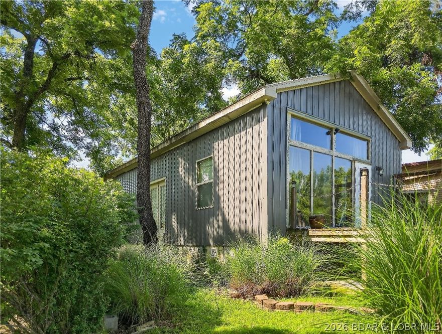 28595 Ochre Street in Warsaw, MO is a charming lake-area retreat ready for its next chapter. This 1-bedroom, 1-bath home offers approx. 1,350 sq ft with a vaulted living area and an unfinished loft/attic ideal for storage or future expansion. Set on a double lot, the property includes a detached garage with workshop space, two additional sheds, and a wood shed - plenty of room for lake toys and projects. Located in the Paradise Point subdivision, owners enjoy access to a boat ramp, community dock with slips available for rent, a community center, and a beach. With a partial lake view just across the street, this is a great opportunity for a weekend getaway, full-time living, or investment near the lake.