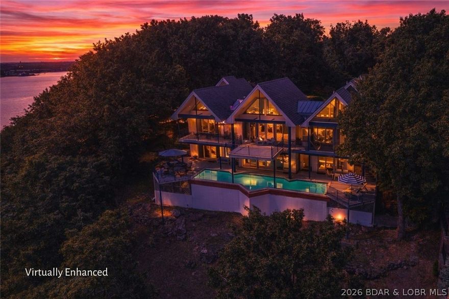 Discover this stunning contemporary masterpiece perched on one of the tallest bluffs at Lake of the Ozarks, situated on an oversized lot next to a common area green belt adding to privacy. Perfectly situated within a secure, gated community, this home offers unparalleled inclusionary views that stretch for miles, making every sunrise and sunset a breathtaking experience. This spacious and impeccably designed residence features five generous bedrooms and five and a half spa-like bathrooms, providing plenty of space for family and guests. The three-car, heated & cooled garage with designer epoxy finished flooring offers convenience, while the meticulously landscaped grounds add to the home's curb appeal. Enjoy a seamless indoor-outdoor lifestyle with a sparkling lap pool, and a 14 x 32 boat slip—ideal for day boating and water adventures. Modern comforts include a whole-house generator, reverse osmosis water system, security alarm system, and contemporary finishes throughout. Whether entertaining guests or relaxing in solitude, this lakeside haven delivers tranquility, luxury, and awe-inspiring vistas at every turn.