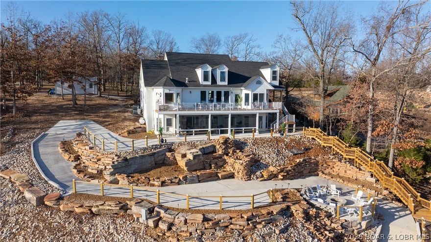 Stunning lakefront retreat on Big Island at Lake of the Ozarks! This fully renovated showstopper sits on approx. 2 acres with 204 ft of shoreline, has a detached 4-car garage, and a private 2 well dock with 3 PWC spaces and swim platform. Offering 5,114 sq ft, 8 bedrooms, and 4.5 baths, the home features main level living, vaulted ceilings, and expansive lakeside windows that fill the space with natural light. The main level master bedroom has its own private en-suite with walk-in in closet. The gorgeous kitchen stands out with stainless-steel appliances, double oven, quartz countertops, new cabinetry, and striking stone accents. Every detail has been updated—flooring, trim, doors, lighting, fixtures, and more. The lower level screened in patio is perfect for those summer afternoons. Outside, enjoy a beautifully transformed landscape complete with a waterfall made of natural rock, firepit, and golf cart path leading to your dock. Brand new roofs have been installed on the home, garage, and dock as well as new siding on the front of the home and the entire detached garage. Breathtaking main-channel views complete this extraordinary lakefront package.