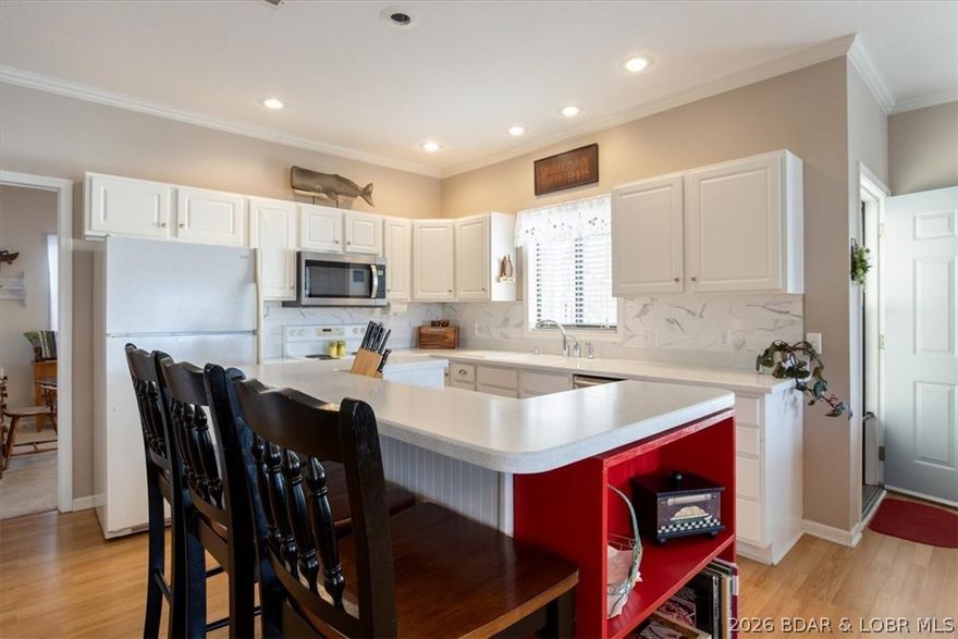 Experience easy lake life in this well-maintained 3-bedroom, 2-bath condo overlooking the Big Niangua Arm at the 9MM. With only 8 gentle steps from parking, you get the rare combination of convenient access and elevated, panoramic views. Inside, the open-concept layout is filled with natural light and features durable vinyl plank flooring, hard-surface countertops, and a comfortable flow ideal for everyday living or entertaining. The primary suite offers a private escape complete with an en-suite bath and walk-in closet, while two additional bedrooms provide space for guests, a home office, or hobbies. A spacious walk-in laundry room with full-size washer and dryer adds extra practicality. Step onto your private balcony to enjoy morning coffee or unwind in the evening as boats pass and the sun dips over the water. Residents enjoy fantastic amenities including a lakeside pool, clubhouse, fitness center, and fishing docks. Sold fully furnished and move-in ready, the condo also includes a private garage for parking and additional storage. Perfect as a full-time residence, vacation getaway, or investment opportunity!