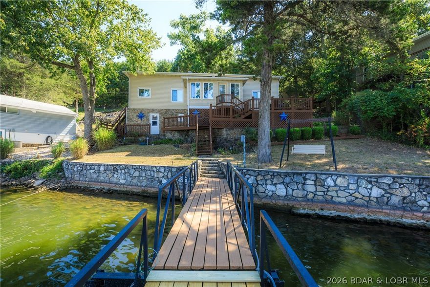 Classic lake vibes with the modern upgrades you’ve been looking for! This beautiful 3-bedroom, 1.5-bath home is ready to impress! Pride of ownership is evident at every turn, with stylish updates and thoughtful touches throughout. The main level welcomes you with a charming sunroom (complete with A/C), updated kitchen featuring tile floors, glass tile backsplash, and updated lighting, plus a bright, open living room with soaring vaulted ceilings. The main-level primary bedroom offers convenience, while two additional bedrooms provide the perfect balance of privacy. The main bath includes both a tub & a walk-in shower. Storage is a standout here, with a spacious lower-level workshop/storage area & additional exterior space for all your lake gear. Step outside & soak up true lake life. Multiple decks, a 2-well dock with boat and PWC lifts, swim platform with wet steps, & 75 feet of stunning stone seawall with easy walkout access. Bonus perks include a second-tier lot with a double carport, HVAC (2019), water heater (2022), and a regularly inspected engineered septic system. This one perfectly blends timeless lake charm with modern comfort. Your lakefront lifestyle starts here!
