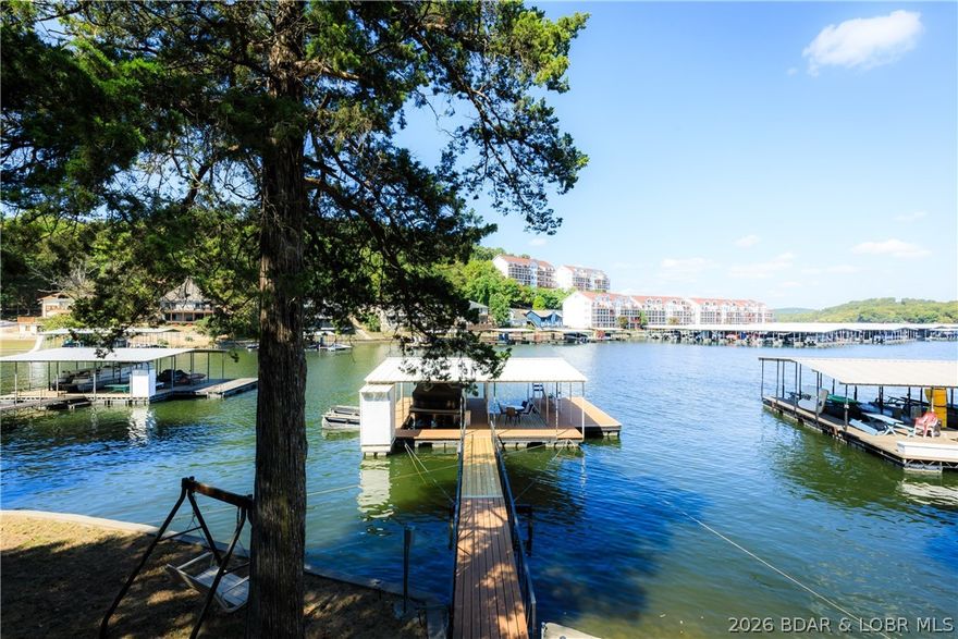 Classic lake vibes with the modern upgrades you’ve been looking for! This beautiful 3-bedroom, 1.5-bath home is ready to impress! Pride of ownership is evident at every turn, with stylish updates and thoughtful touches throughout. The main level welcomes you with a charming sunroom (complete with A/C), updated kitchen featuring tile floors, glass tile backsplash, and updated lighting, plus a bright, open living room with soaring vaulted ceilings. The main-level primary bedroom offers convenience, while two additional bedrooms provide the perfect balance of privacy. The main bath includes both a tub & a walk-in shower. Storage is a standout here, with a spacious lower-level workshop/storage area & additional exterior space for all your lake gear. Step outside & soak up true lake life. Multiple decks, a 2-well dock with boat and PWC lifts, swim platform with wet steps, & 75 feet of stunning stone seawall with easy walkout access. Bonus perks include a second-tier lot with a double carport, HVAC (2019), water heater (2022), and a regularly inspected engineered septic system. This one perfectly blends timeless lake charm with modern comfort. Your lakefront lifestyle starts here!