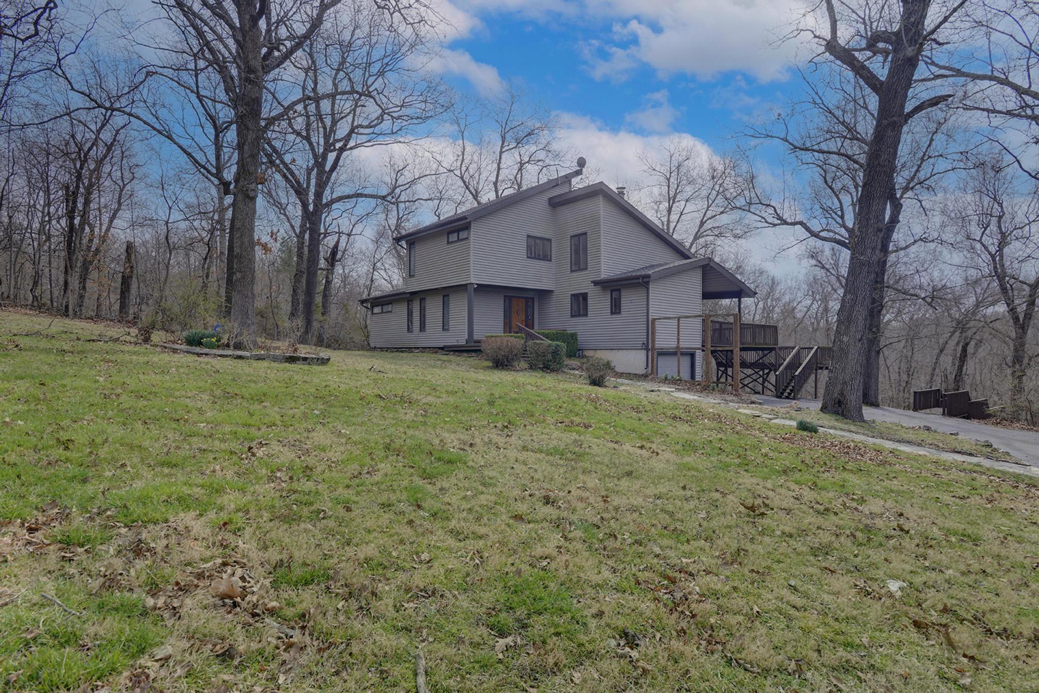 ***3/27 OPEN HOUSE CANCELED***Amazing, contemporary home on just under one acre in a desirable area between Springfield and Rogersville with an amazingly flexible floor plan!  Prepare to be wowed when you walk in and are greeted by the open staircase and the beautiful wood floors that lead to the soaring two-story living room with wood burning fireplace and floor to ceiling windows with views of the amazing wooded lot and huge deck behind! The large kitchen features tile flooring, loads of cabinetry, a built-in oven and a large island with cooktop range. This home can be used in many different configurations.  It can be used as a four bedroom home with the upstairs loft functioning as the third bedroom and the finished basement space as the fourth.  Or it could be used for as little as two bedrooms with three living spaces instead! The flexibility is endless! The main floor features the kitchen, living room, laundry room, a guest bedroom, full guest bath with walk-in shower and the full master suite complete with walk-in shower. The upstairs loft features a fantastic wood stove, beautiful wood floors and a full bath. It could be used as an office, a living area or a bedroom. The beautiful staircase leads to the basement as well which features a storage area, the garage, half bath and the large flex space which would easily be a fourth bedroom or second/third living area.  This wonderful home shines in the great outdoors aspect as well as it shines indoors! The beautiful lot is partially wooded and there is a huge back deck to enjoy the scenery and wildlife of the Ozarks.  The home does need a bit of TLC and is priced accordingly and also sold As-Is. The roof is believed to be under two years old and the HVAC has been replaced very recently as well. Don't wait, call today for your private tour!!!