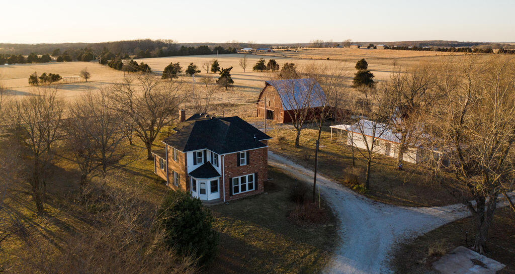Located under a mile off of Highway 65 just south of Urbana sits this beautiful property with endless possibility. Tucked in off of State Highway HH you'll find a park like setting with a beautiful home, spacious yard, mature trees, and 4 different buildings. The home has over 2,100 square feet of living space and includes an updated kitchen and 1 bedroom and full bath on the main level. The second level includes 3 spacious bedrooms and a full bath with plenty of windows that create an abundance of natural light and beautiful views of the property. A short walk out the back door will bring you to a 24'x45' workshop that includes 100 amp power, water, and plenty of space to store lawn equipment and tools. There is also a 30'x50' shop that includes 100 amp power, steel frame, and a 12' overhead door. The shop also includes a 12' overhang for additional storage under roof. Behind the workshop sits a small A-frame building that has access to all utilities necessary (power, water, sewer) to create a small guest house. The most unique building is the original barn that is 35'x50' and in excellent condition.The land is level to gently rolling and is productive with over 90% being comprised of Class II tillable soils. The fields are currently planted in Bermuda grass and produced over 120 5'x6' round bales in the first cutting of 2021. Running livestock is also an option with perimeter and cross fencing, including steel corners around the perimeter of the property. Water is abundant with 3 ponds and two automatic waterers that offer a reliable water source for livestock. The northeast portion of this tract includes a small area of timber that ranges from mature oaks to dense cedars. The variety of habitat creates an excellent area to hold wildlife. Deer sign can be found throughout the timber with multiple rubs, scrapes, and trails. The west side of the property also gives you another access point to County Road 415.