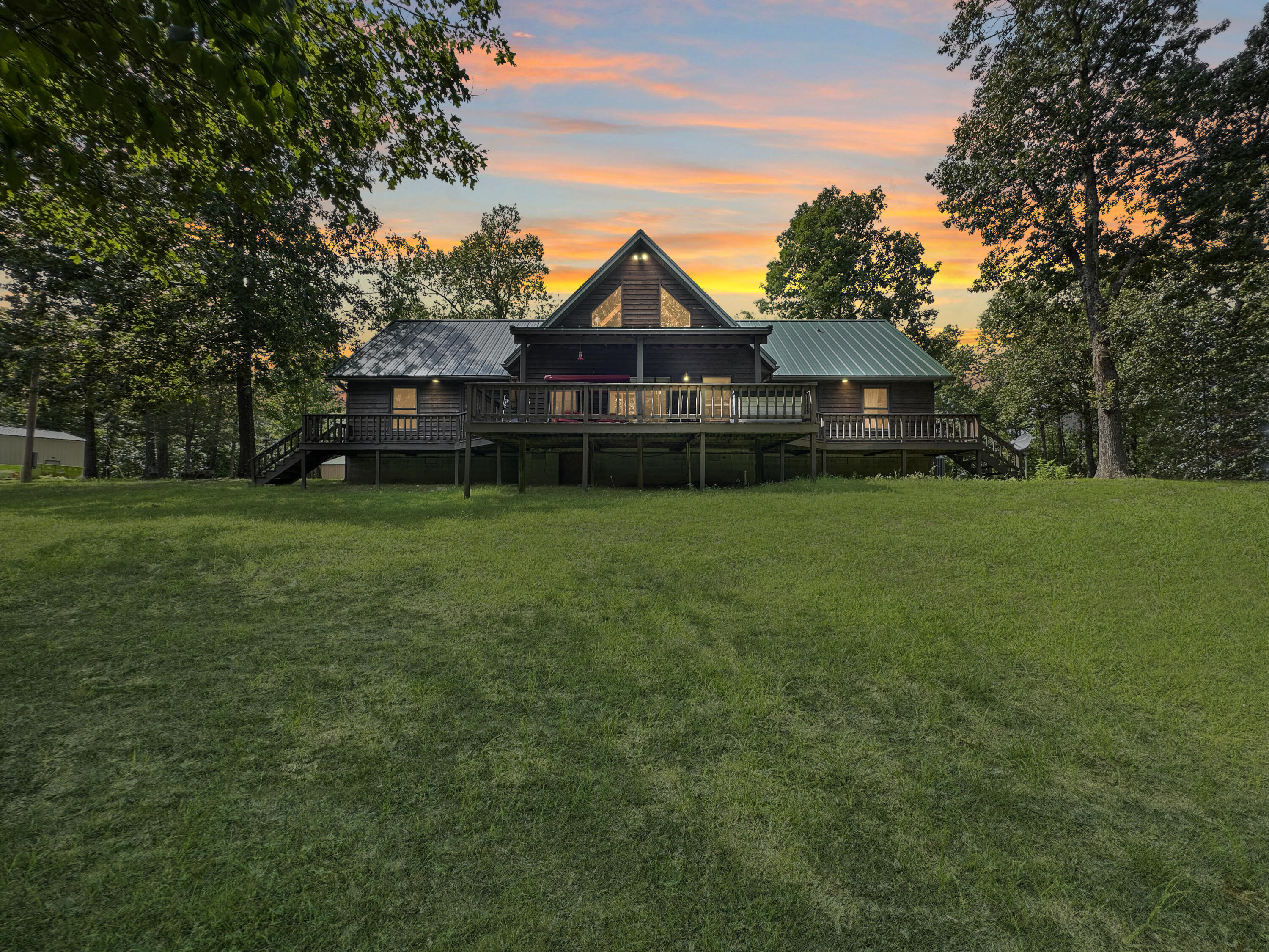 This rustic chalet style home offers a unique blend of seclusion and luxury. Located on the Bull Shoals lake (Corp of Engineer government frontage) and features hiking and ATV trails close by. The driveway is secluded and leads to the house, which is surrounded by trees and has 5 acres cleared around it. The property also boasts two detached shops, one of which is a 24 x 30 RV garage and the other is a 50 x 30 insulated & air-conditioned workshop. The house itself has a 1/2 story upstairs loft area. This space could be used for spare bedrooms or as a cozy reading nook. This property offers a lot of opportunity for those who enjoy outdoor activities, ATV, and hiking, and want a home with land. Located on one of the best fishing lakes in rural Missouri, this property is minutes away from Theodosia where one can access the city's amenities.