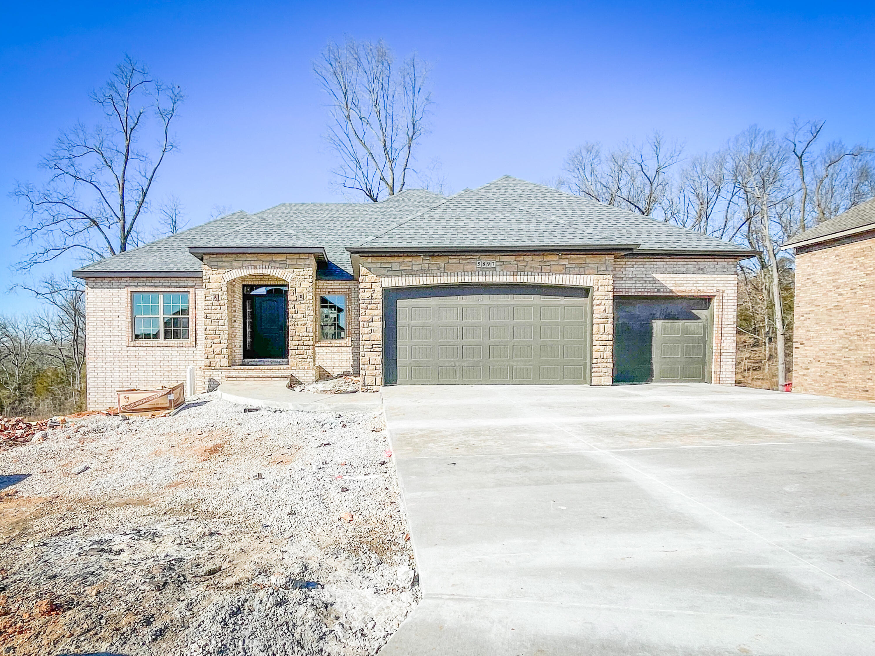 Brand new home in Beautiful Gated Lions Gate! Backs up to trees! 5 BR , 3 1/2 baths, walkout basement! It can be a 30-day closing no problem. All brick/stone exterior with a two tier deck with contemporary cable accents. The interior flooring is engineered wood, Granite countertops, beautiful trim and doors, gorgeous all wood cabinetry with soft close doors and drawers and all hidden hinges.  There are 2 laundry rooms one on each level. There is John Deere room in the basement. This home Apprx 4000 Sq ft. This home will have all wooden shelving in bedrooms and the pantry. 3 BRs on main level with 2 additional in basement. Multiple living areas including family room in the basement. The appliances are Stainless and include gas range, dishwasher, microwave & offers a walk-in pantry with wooden shelves in kitchen. The front and side yards will be sod & Irrigation, the back will be seed and straw. This builder insulates the garage walls, garage doors and in the attic above the garage and He also vents his hood above of the stove to the outside. Very few builders do either of these items his are standard. The garage door openers are smart openers so you will never worry about your garage door being open after leaving for a trip. You will want to come and look at this home and claim it before it is gone.