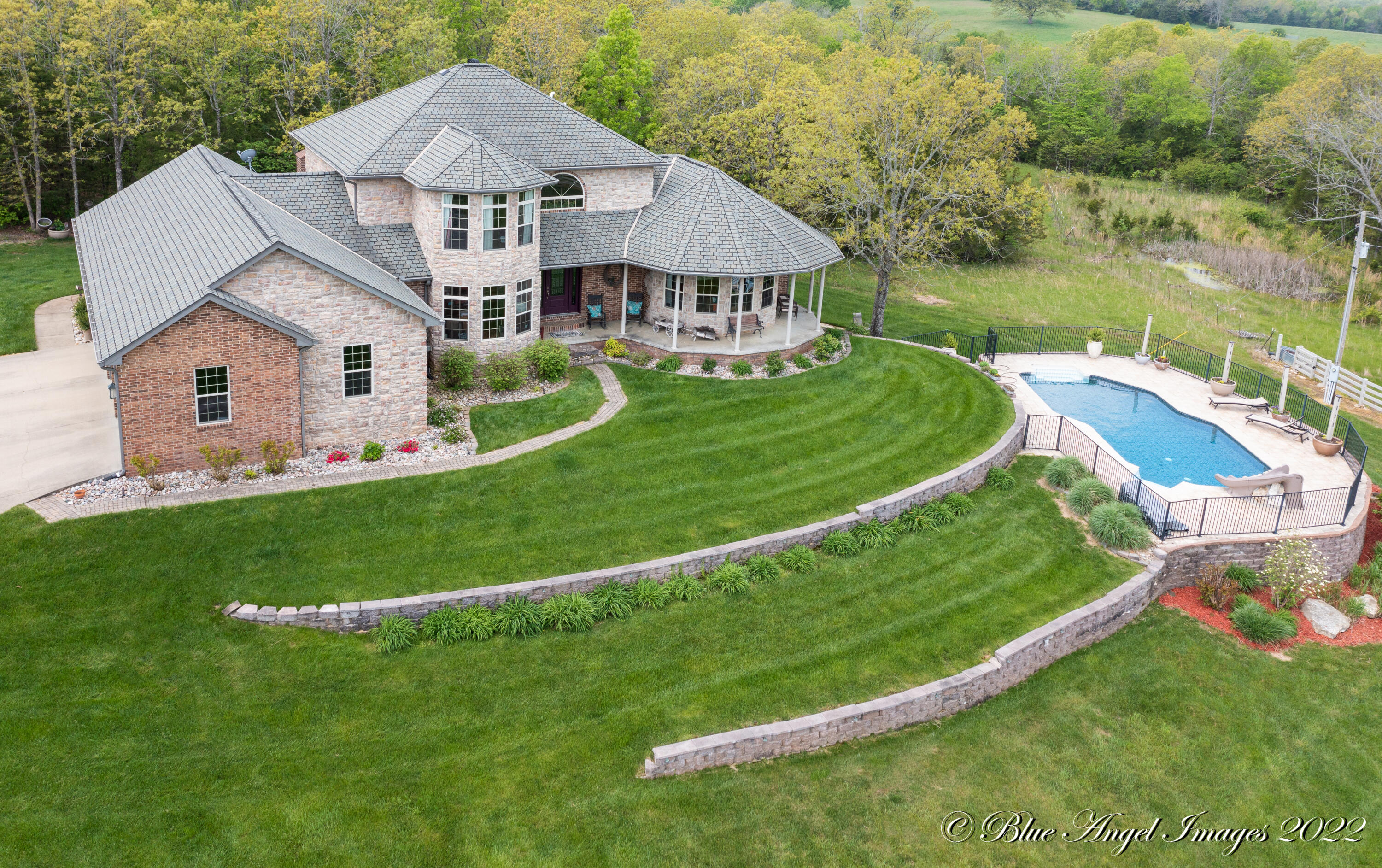 Check out this stunning all brick ultra-modern home situated on 24 acres located just minutes from town! Inside this beautiful home you will find absolutely no expense spared! Starting with the chef-grade appliances, large laundry room w/sink, custom oak cabinetry, exposed beam ceilings, oak hardwood floors, large master bedroom, and office all on the main level. Head upstairs to find 2 more generous bedrooms and lookout over your vaulted living room ceiling to the rock fireplace. Downstairs features a full kitchen, media room, utility room with 3 duel fuel HVAC units, two bedrooms, and walkout access to your very own pool! The inground pool features 3' shallow end and 8' deep end with a built in slide and winter cover. Outside you will also enjoy your own private outdoor fireplace and plenty of covered patio space. Pull up your private paved driveway to find parking is no issue with this property boasting an oversized attached 3 car garage as well as 35'x26' three car detached garage. The land features perimeter fencing as well as a pond and small stable for all your animal needs!