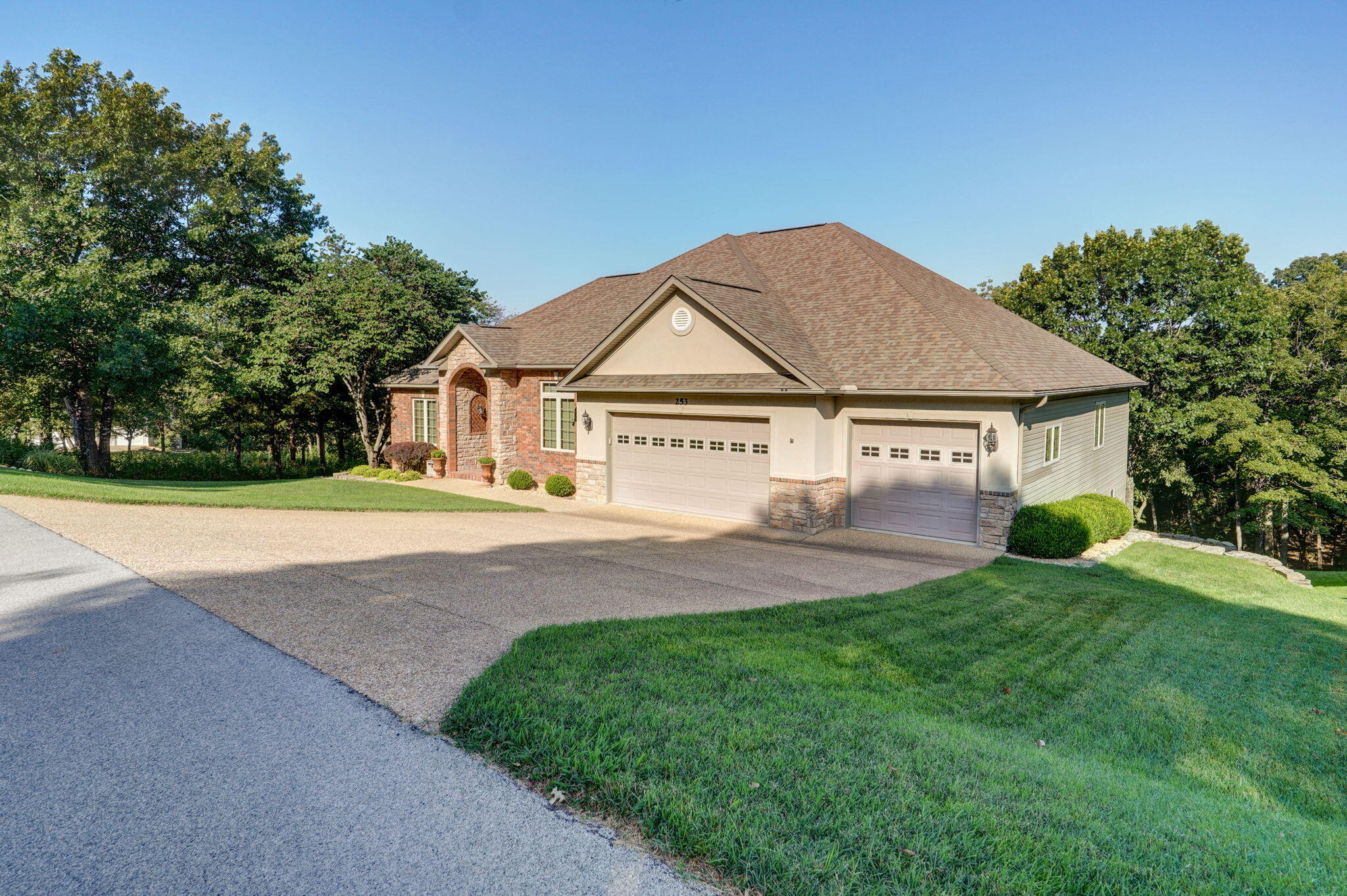 Amazing, finished walkout basement home in a semi-secluded setting is on LAKEFRONT with a 10 x 24 boat slip available. Overlook Subdivision separates itself from most - offering many amenities including in-ground pool, clubhouse, long-term trailer & boat parking, community water system, as well as excellent HOA and POA structure. The exterior of the home offers a fantastic blend of planned landscaping and Table Rock Lakes natural beauty. Beginning with sharp curb appeal concrete & pebble driveway, brick - stone - and touch of stucco front, covered front porch, low E gas windows with UV protectant, front sprinkler system, wide 3 car garage (with attached extra insulation, shelving, tub sink, & workbench), and groomed front yard. The rear exterior is an oasis - hosting nearly 21 species of birds, deer families, resident bat that reduces mosquitos, excellent shoreline fishing, mature trees, clear pathway to shoreline for easy access, large & terraced limestone boulders, remarkable composite covered & open deck - so nice, covered & open expanded patio. Spending time in the back yard is worth visiting the property - so relaxing. The inside is meticulous in the owner's care. This easy keep home offers so many options regarding rooms & living spaces.... the main level offers a wide & inviting entryway (with raised ceilings and crown molding), formal dining area (with well-kept engineered wood floors, coffer ceilings, & crown molding), large living room (with archways, see-through gas fireplace with stone & wood mantel, crown molding, dimmable lighting, excellent flow to open kitchen & dining / sunroom), cozy sunroom (with fantastic view of seclusion complete with lakeview, fireplace, and a real sense of peace). The open kitchen & dining (with triple & transom windows for lakeview, easy access to covered deck, black & stainless appliances, trash compactor, black composite sink with lakeview, granite countertops, granite island...