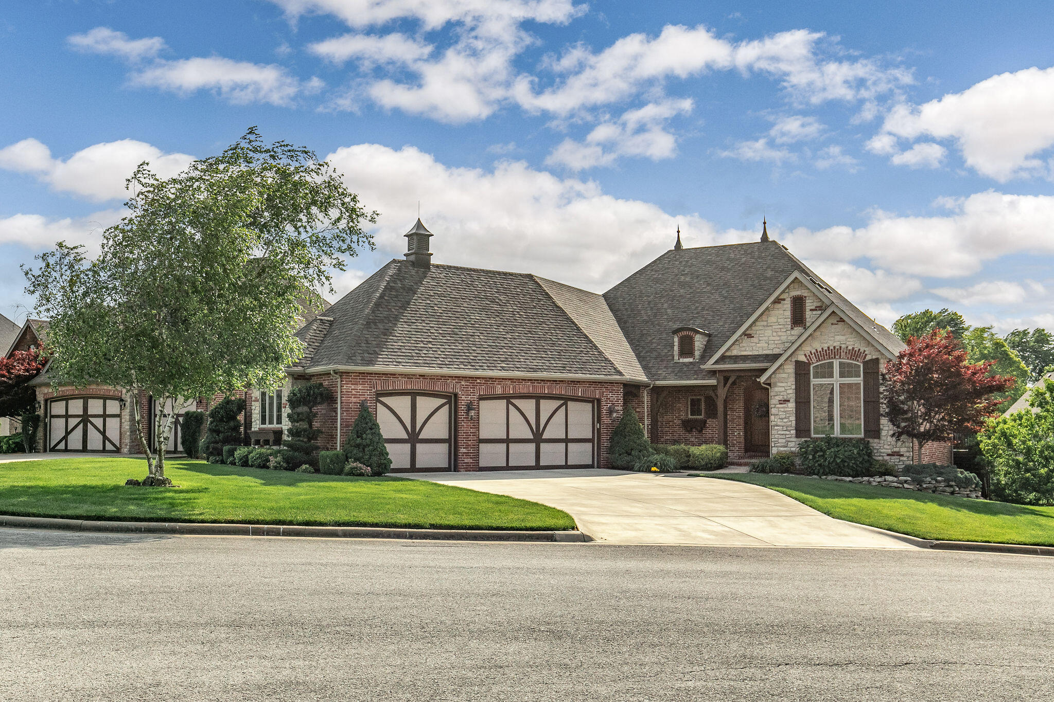 Custom brick and stone home in Village at Wicklow!  Built by Cornerstone Cottages, this home features 4 beds + office, 3 baths, 3 car garage, and brand NEW roof January 2022!  No detail was missed in this beautiful home.  Walk in to an office with vaulted ceilings, French doors, and beautiful hardwood floors.  The high ceilings continue through the living room with a stone fireplace and open floor plan to the kitchen and dining area.  Kitchen features beautiful wood cabinets, extra bar seating, walk-in pantry, and stainless steel appliances.  The primary suite has gorgeous tray ceilings, his and her vanities, jetted tub, walk-in shower, and a large walk-in closet. The main level has 1 more bedroom, a full bathroom, and a great sized laundry room with sink and extra cabinets!  The walk-out basement offers a 2nd stone fireplace, family room, wet bar, theater room with surround sound, workout room, and John Deere room!  It also has 2 additional bedrooms, and a full bathroom!  Outside, enjoy the main level covered deck with stairs down to a lower level patio.  The landscaped yard has a full wood fence and irrigation system.  Located on a quiet road minutes from Fremont Hills Country Club and Nixa Community Center, this is a must-see property!