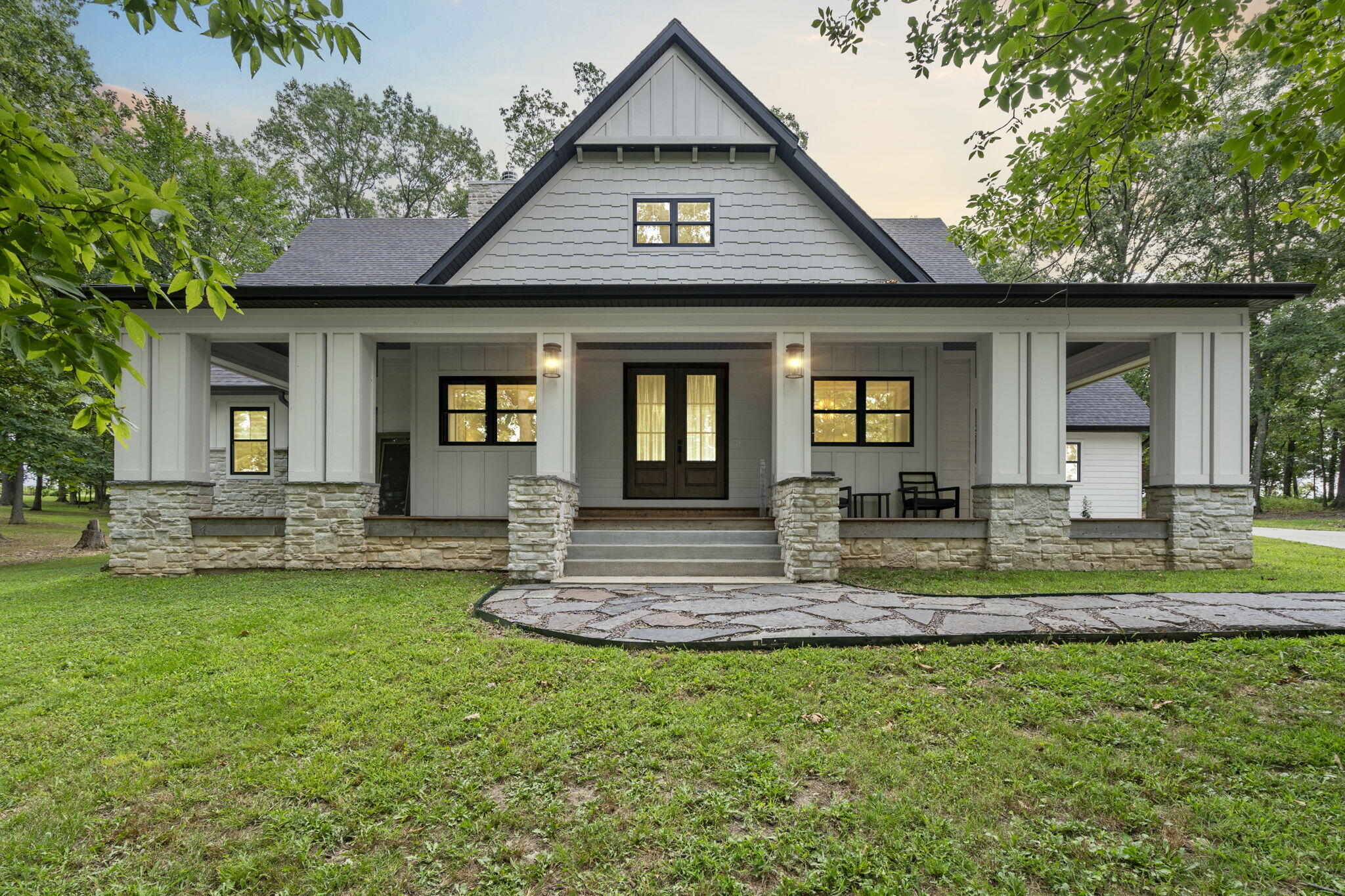 Welcome to 235 Kings Ct.! This custom-built 2018 residence sits on nearly 6 acres. As you enter, you're greeted by soaring 26 ft. ceilings and a floor-to-ceiling tiled wood-burning fireplace. The gourmet kitchen boasts wood and white slow-closing cabinetry, porcelain tile slab countertops, a tile backsplash, eye-catching light fixtures, and expansive island seating at one of the two islands. Adjacent to the kitchen, the dining room features a large bay window with seating and storage. A spacious mudroom off the garage entry adds convenience.The main floor master suite features a large walk-in shower, walk-in closet, double vanity, and custom cabinetry with a built-in vanity. An additional bedroom, guest bathroom, and powder room complete the main level. The beautiful wood staircase with iron railing leads to the second floor, where a built-in desk feature awaits. Upstairs, you'll find three more bedrooms, a full bathroom with double vanity and walk-in glass shower, a designated office, and another living space. The home is adorned with masterfully installed tongue and groove oak floors.Designed for modern living, this home features dual zoned HVAC with two 16 seer heat pumps with propane backup along with high-efficiency spray-foam insulation, ensuring a low electric bill. The property also features a 500 gallon underground propane tank, and is plumbed for a central vacuum. The craftsman-style exterior includes a large covered front porch and a screened-in back porch, perfect for relaxing in the serene, park-like setting.Additional amenities include a three-car garage, a 30amp RV connection, a custom chicken coop, and a garden. Only a few minutes from Ozark Elementary East, this property is located with convenience in mind. With multiple living spaces and a built-in theater system room, this home is ideal for both entertaining and everyday living. Don't miss the opportunity to witness the gorgeous sunset views from this property!